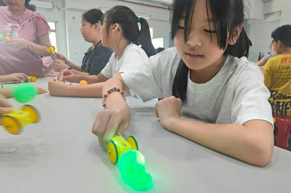 學童透過摩擦發電裝置點亮 LED，體驗能源轉換原理。