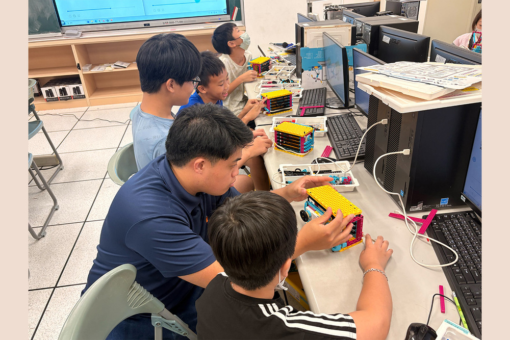高科大USR計畫團隊學生李秉宸帶領壽齡國小學童運用樂高積木與SPIKE設備，模擬保險箱應用情境，體驗科技實作。